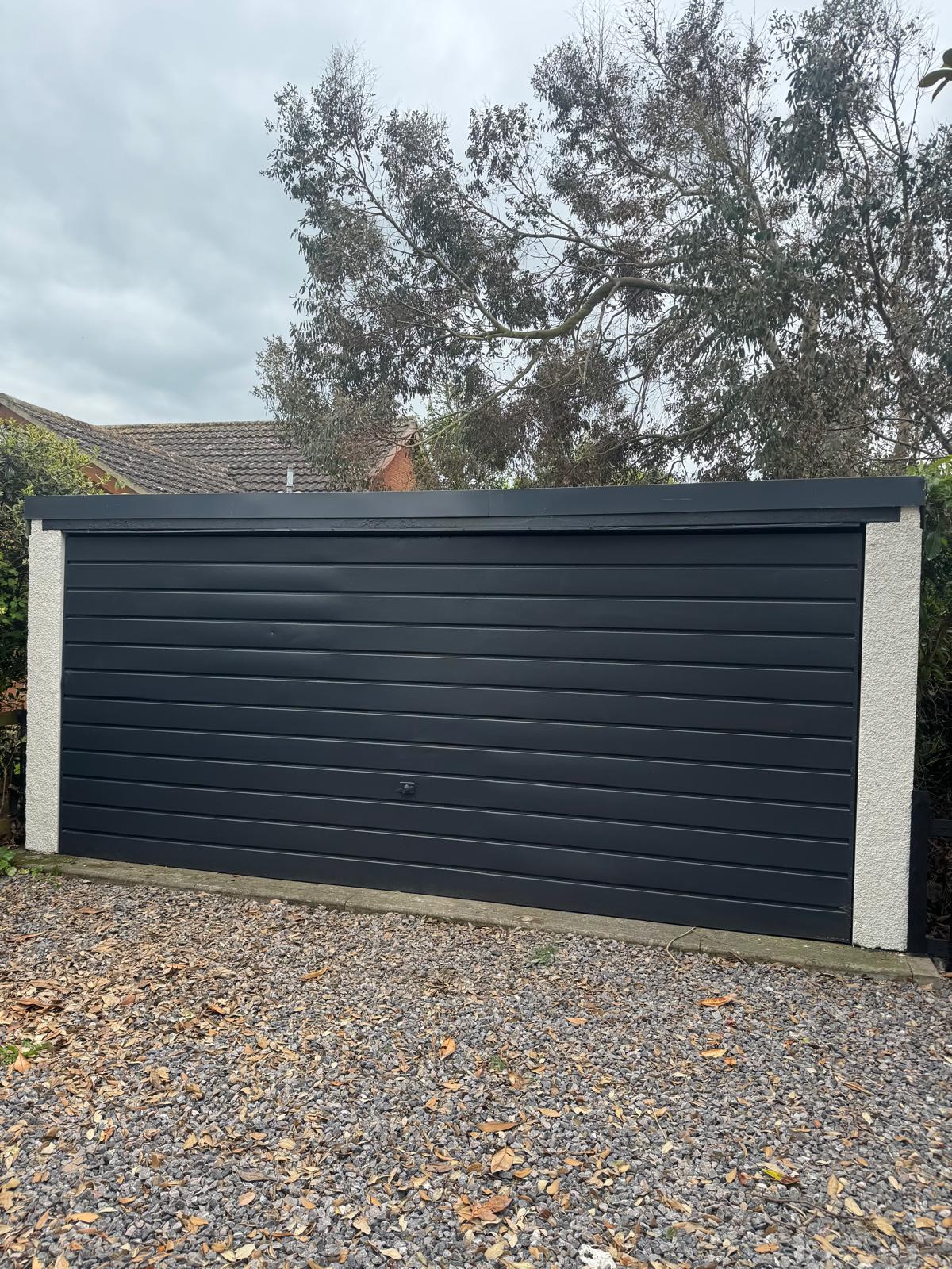 Dark colored garage door with white posts