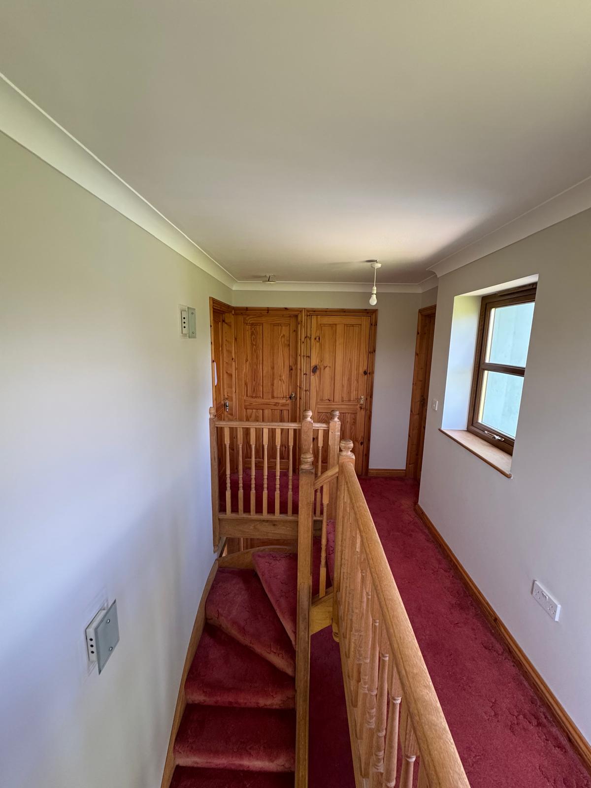 Upstairs hallway with white walls and wooden staircase