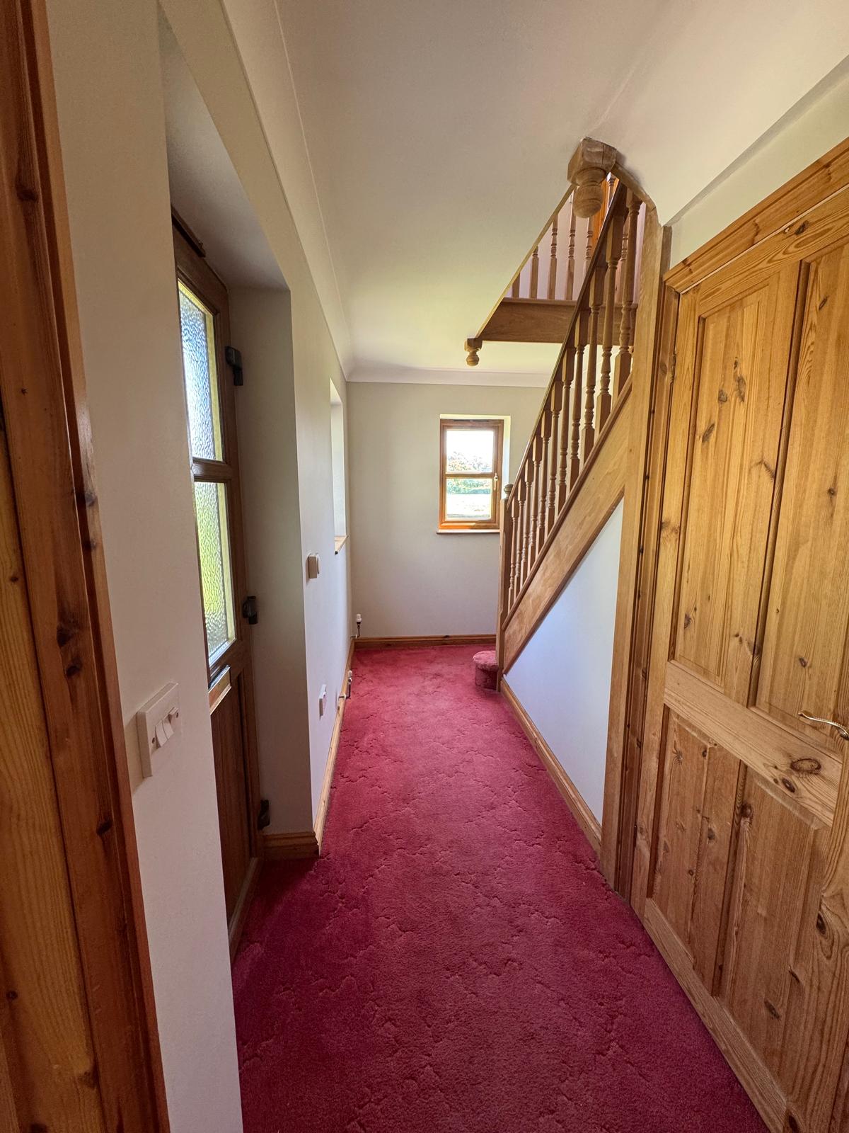 Hallway with wooden staircase and red carpet