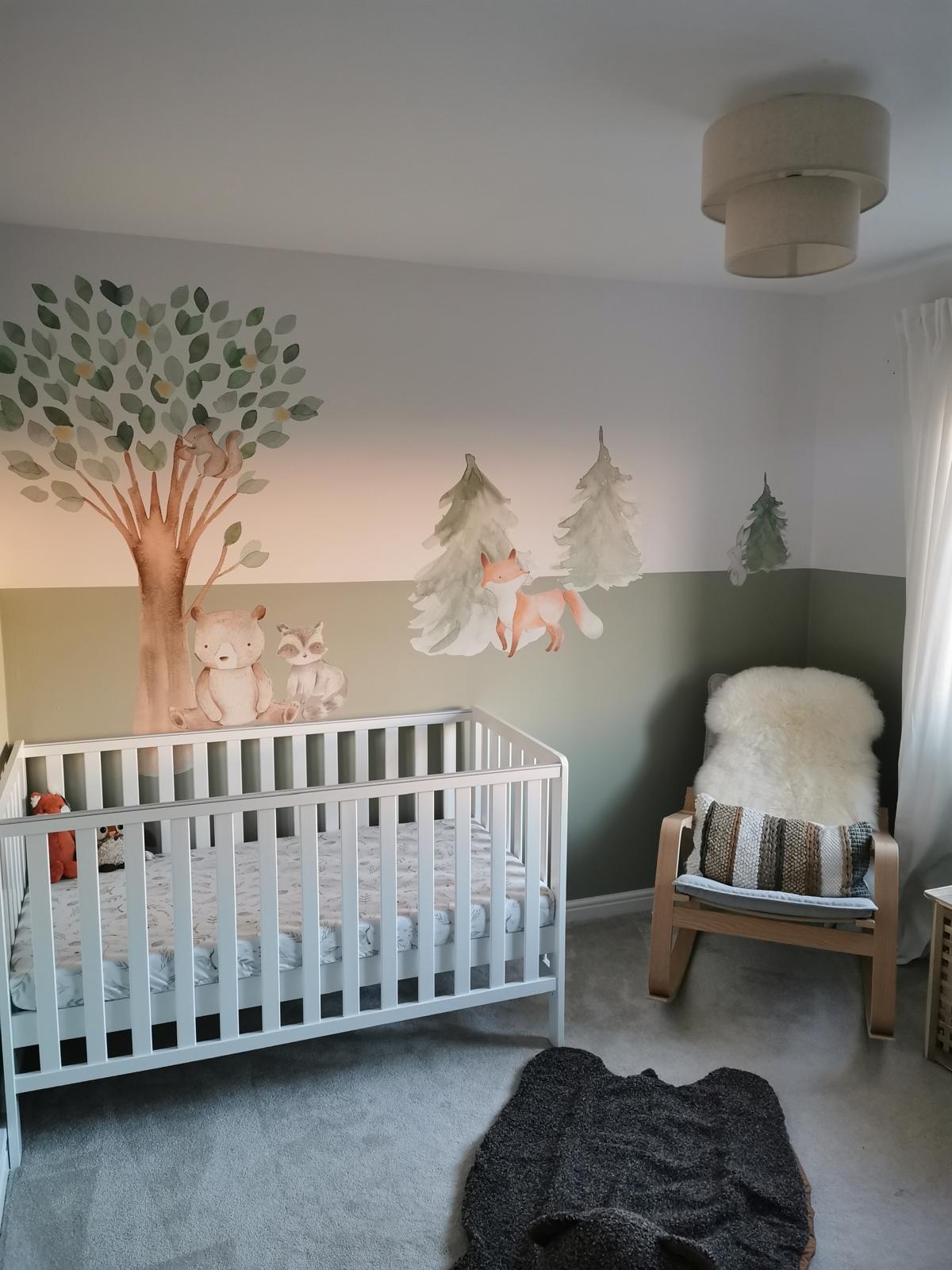 Baby nursery with sage green feature wall and woodland wall decals
